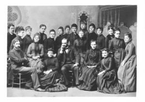 A black and white formal portrait shows a group of twenty-one individuals, mostly women in long dresses and a few men, posing for a "Library school class of 1890."