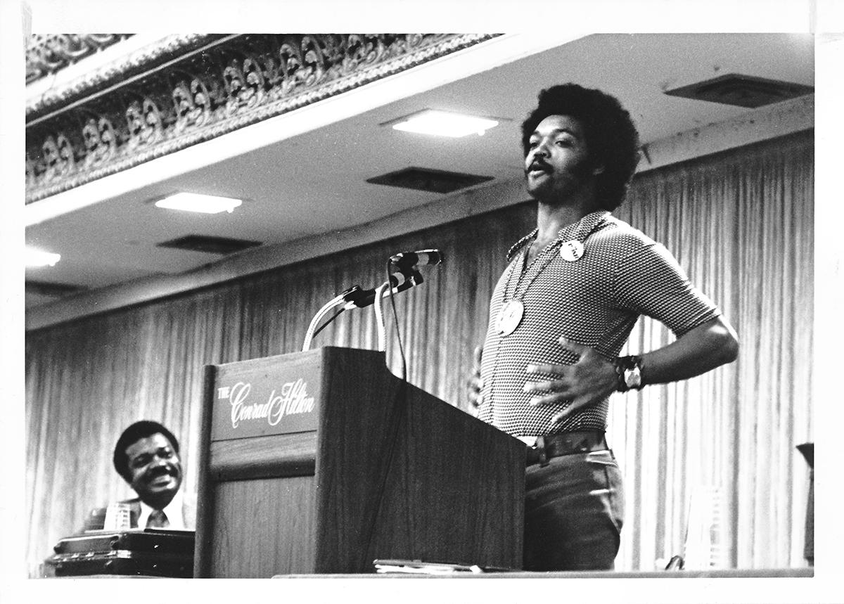 Black and white archival photo of a young Rev. Jesse Jackson standing at a podium
