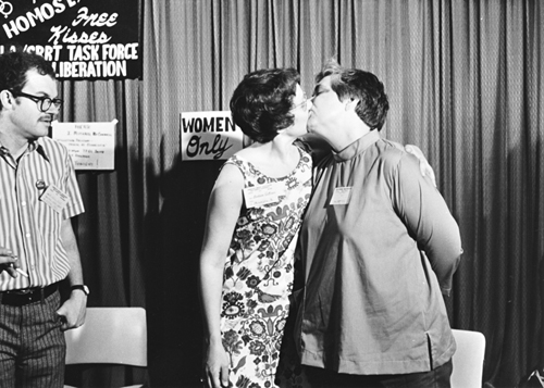 Barbara Gittings and author, Isabel Miller (Alma Routsong), kiss at the Task Force on Gay Liberation's kissing booth at the ALA Annual Conference in Dallas 1971. From the ALA Archives.