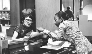 A library worker helps a patron at the reference desk of Detroit Public Library, circa 1976. From the ALA Archives.